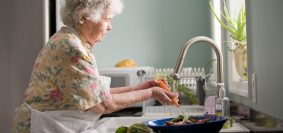 woman wearing yellow and pink floral dress wahing carrots